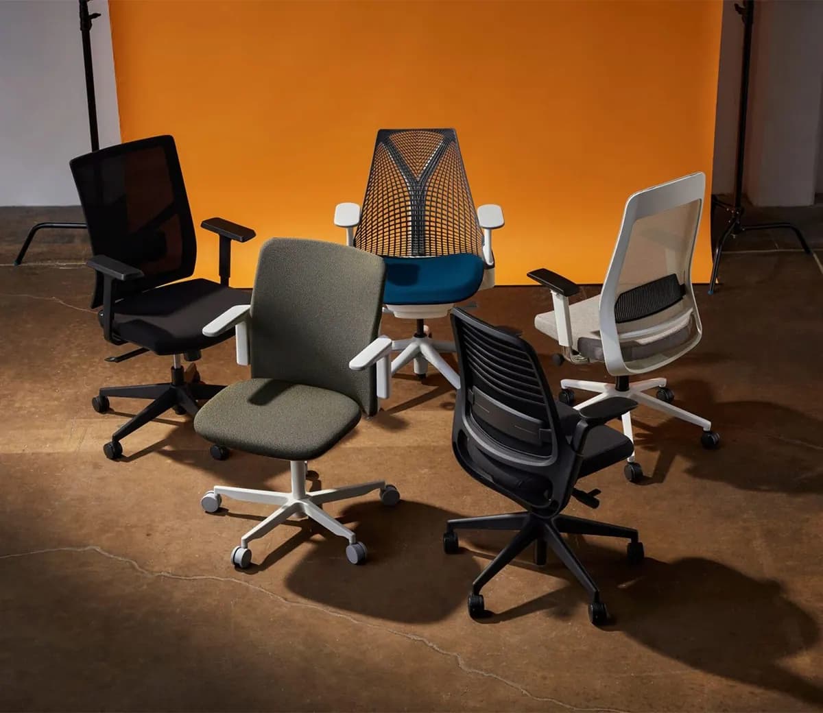 Karrige zyre ergonomike të rreshtuara në një dhomë të errët.